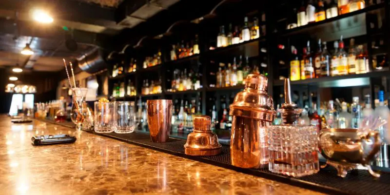 A bar with many copper cocktail shakers and bottles.