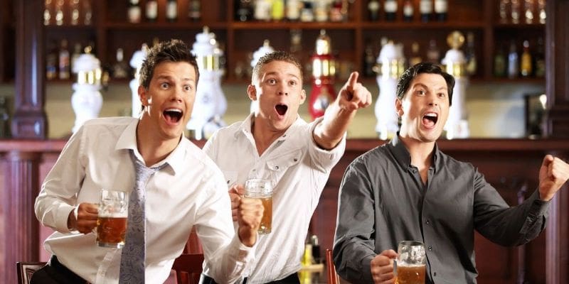 Three men are watching a game in the bar.