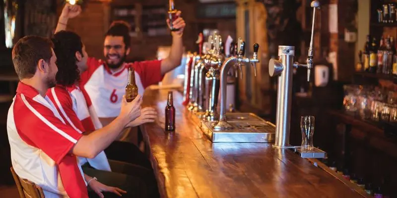 A man holding up his beer at the bar